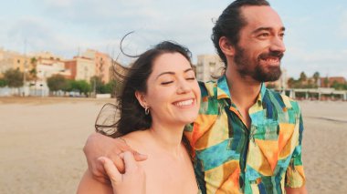 Birbirini seven bir çift kumsalda yürüyor ve sarılıyorlar.