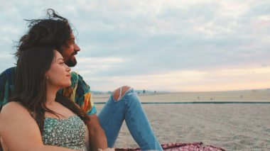 Birbirine aşık çiftler kumsalda güneşin doğuşunun tadını çıkarırlar.