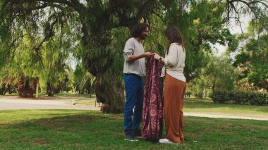 Yeşil çimlerde piknikte battaniyeli çift