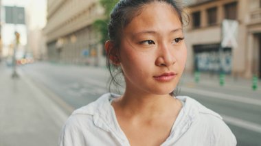 Yakın plan, genç bayan yolun kenarında dururken cep telefonu kullanıyor. Kız etrafına bakıyor.