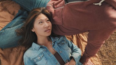 Dışarıda, parkta battaniyeye uzanmış genç bir çiftin yakın çekimi. Üst görünüm