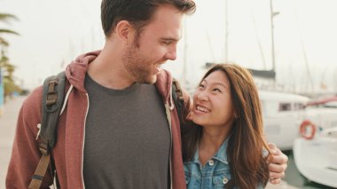 Birbirine aşık bir çift limanda el ele yürüyor.