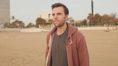 Genç adam sahilde yürümekten hoşlanıyor.