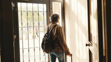 Orta yaşlı bir adam bavuluyla evden ayrılıyor.