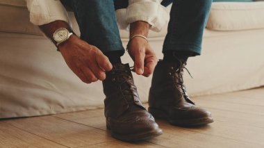 Yetişkin bir adamın ayaklarına yakın plan çizmeler giyer, ayakkabı bağları bağlar.