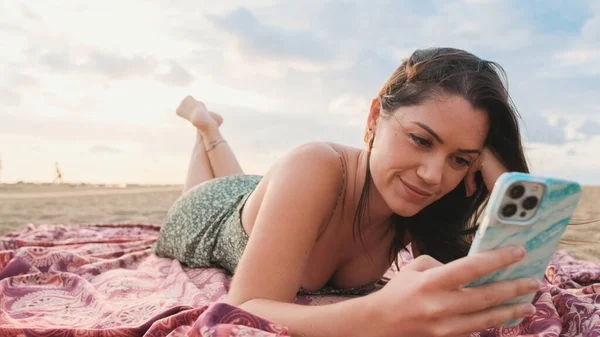 Młoda Uśmiechnięta Kobieta Relaksuje Się Plaży Korzysta Telefonu Komórkowego — Zdjęcie stockowe