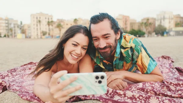 ビーチで携帯電話を使ってビデオ通話をする男と女 — ストック写真