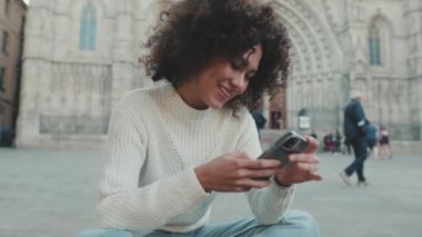 Genç bir kadın cep telefonunu kaydırıyor.