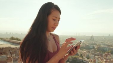 Kapatın, genç bayan gözlem güvertesinde dururken cep telefonu kullanıyor.