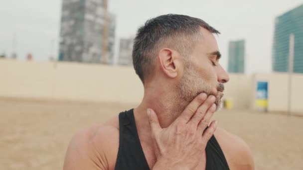 Man Works Out Beach Stretches Neck Muscles — Stock Video