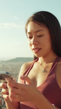 Gözetleme noktasında dururken cep telefonu kullanan mutlu atletik kadın.