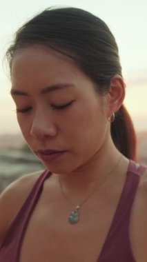 Yakın çekim, kız şafak vakti izleme platformunda otururken meditasyon yapıyor.