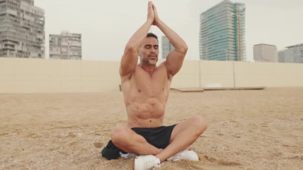 Зрілий Чоловік Робить Дихальні Вправи Сидячи Піску Узбережжі — стокове відео