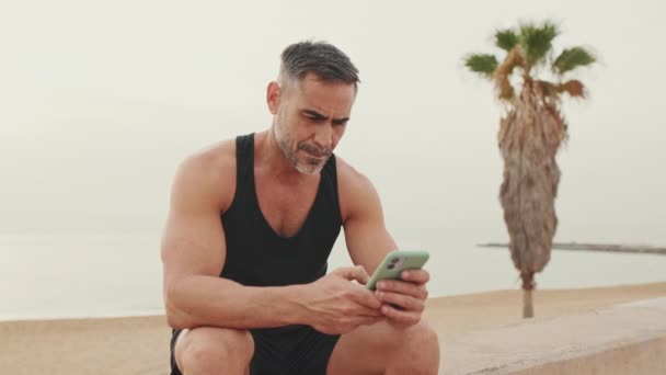 Зрілий Чоловік Спортивному Одязі Використовує Мобільний Телефон — стокове відео