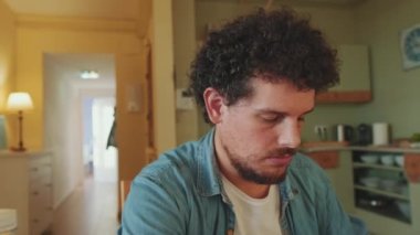 Genç adamın sıcak mutfakta otururken yemek yediği yakın çekim.