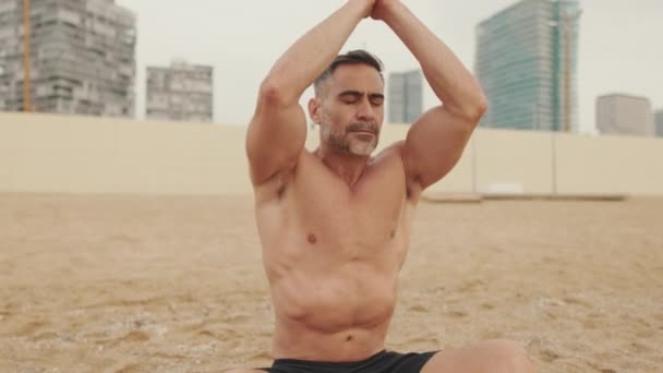 Ώριμος Άντρας Κάνει Ασκήσεις Αναπνοής Ενώ Κάθεται Στην Άμμο Στην — Αρχείο Βίντεο