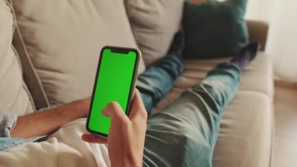 携帯電話を使用してソファに横たわっ男の手のクローズアップ — ストック動画