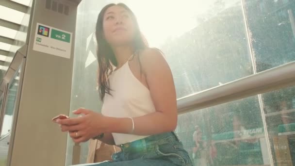 Молода Жінка Сидить Зупинці Громадського Транспорту Використовує Мобільний Телефон Дивиться — стокове відео