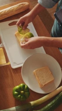 Mutfakta duran genç bir adamın sandviçini yakından çek.