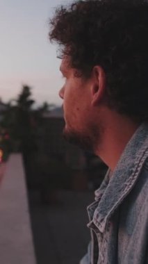 Balkonda dikilen genç adamın yakın çekimi.