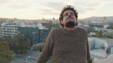 Gülümseyen genç adam balkonda duruyor.