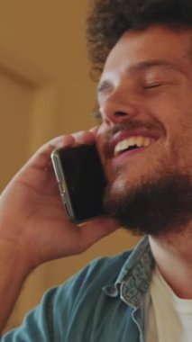 İçeride cep telefonuyla konuşan mutlu genç adamın yakın çekimi.