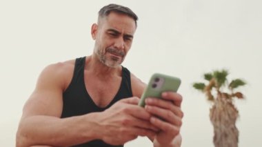 Spor giyim sektöründe olgun bir adam cep telefonu kullanıyor.