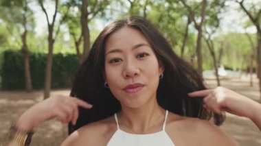 Genç bir kadının saçlarına dokunup gülümsediği yakın plan.