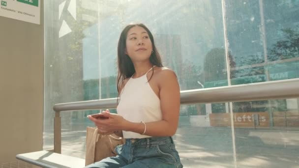 Genç Bir Kadın Toplu Taşıma Durağında Oturuyor Cep Telefonu Kullanıyor — Stok video