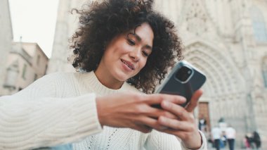 Yaklaş, genç kadın bir cep telefonuna kayıyor. Mutlu kız eski şehir geçmişinde cep telefonu kullanıyor.