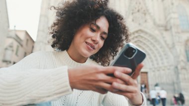 Yaklaş, genç kadın bir cep telefonuna kayıyor. Mutlu kız eski şehir geçmişinde cep telefonu kullanıyor.