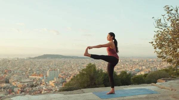 stock image Girl practices yoga stands on one leg at lookout point at dawn