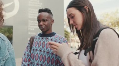 Close-up of a guy and a girl talking to each other and using a mobile phone