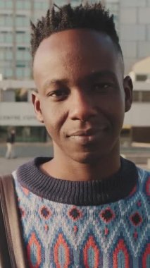 Kameraya bakıp gülümseyen genç bir adamın yakın çekimi.