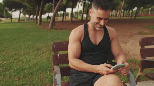 Сміється Чоловік Середнього Віку Спортивному Одязі Читає Повідомлення Мобільному Телефоні — стокове відео