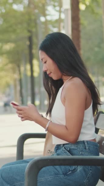 Jonge Vrouw Zit Parkbank Typt Bericht Mobiele Telefoon — Stockvideo