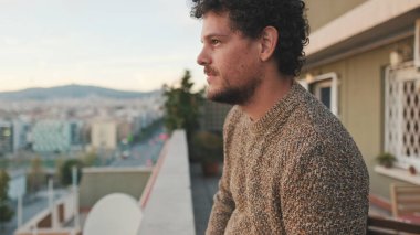 Mutlu adam balkondan şehre bakıyor, güzel manzaranın tadını çıkarıyor.