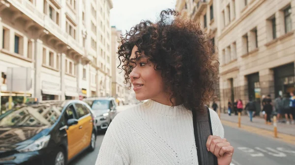 stock image Young female tourist is walking along a crosswalk. Girl with a backpack crosses the road at a pedestrian crossing looking around