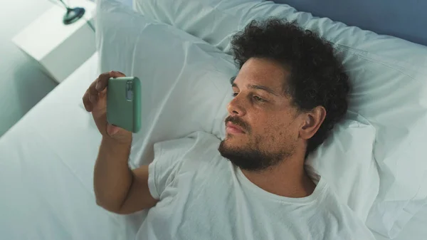 Kerl Liegt Mit Ihrem Handy Auf Dem Bett Und Schaut — Stockfoto