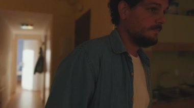 Genç adam dairesinde mutfağa gelir.