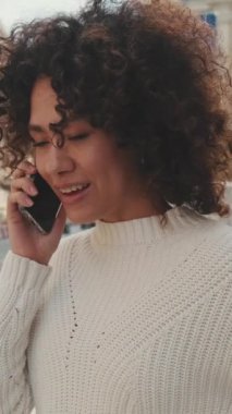 Dikey video, yakın çekim, cep telefonuyla konuşan genç kadın.