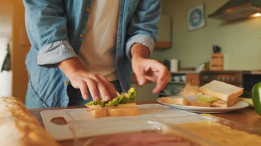 Mutfakta dikilirken kot gömlekli bir adamın sandviçi pişirmesi. 