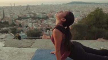 Genç bir kadın gün doğumunda izleme platformunda yoga yapıyor. Yılan pozisyonunda bir kız.