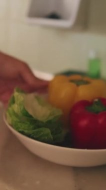 Elinde bir kase yıkanmış sebze tutan tanınmayan bir adamın ellerine yakın çekim.