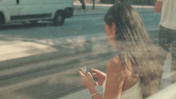 Ung Kvinna Sitter Vid Kollektivtrafiken Stopp Använder Mobiltelefon Suddig Utsikt — Stockvideo
