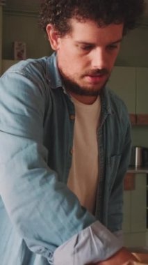 Genç adam mutfaktaki eşyalarını boşaltıyor.