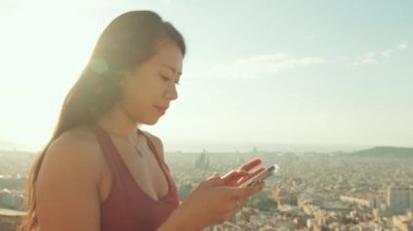 Gözlem güvertesinde dururken cep telefonu kullanan genç bir kadın. Arkaplan