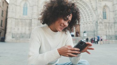 Yaklaş, genç kadın bir cep telefonuna kayıyor. Mutlu kız eski şehir geçmişinde cep telefonu kullanıyor.