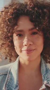 Student with notebooks in her hands looks at the camera and smiles