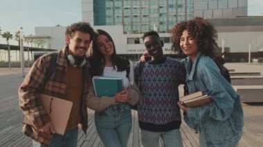 Group of students smiling while looking at camera while standing outside